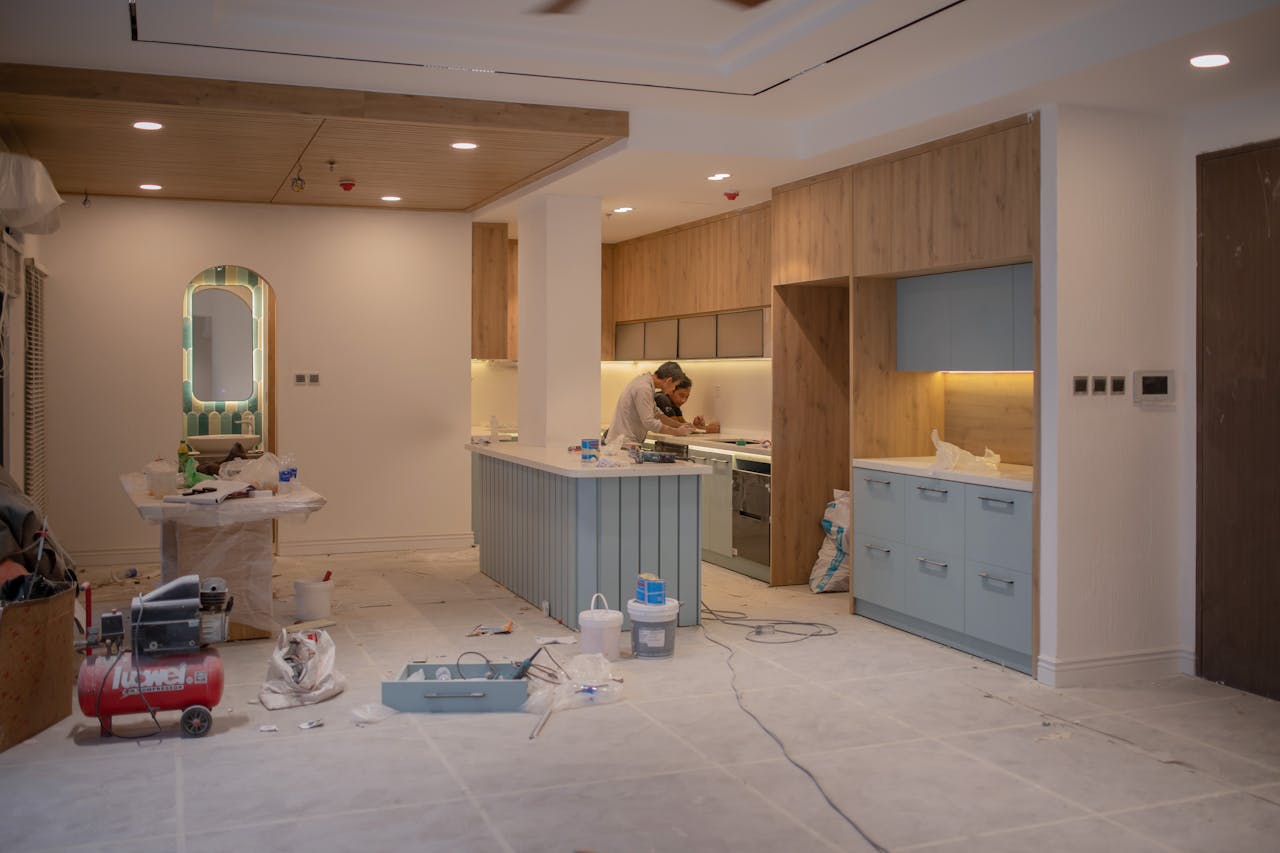 about-us A modern kitchen undergoing renovation, featuring a worker, tools, and materials.