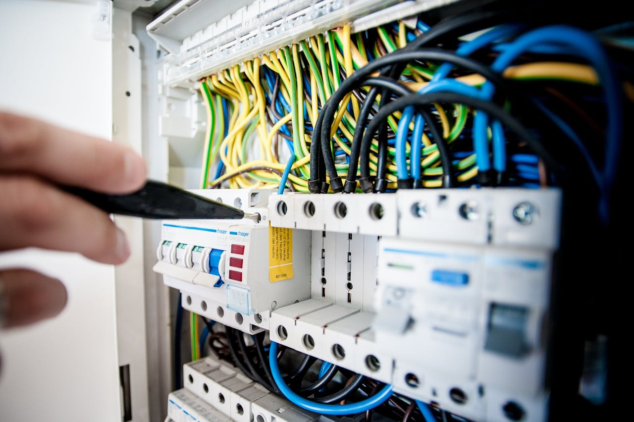 services-01 Hand of electrician working on a circuit breaker panel with colorful wires, ensuring safe electrical connections.